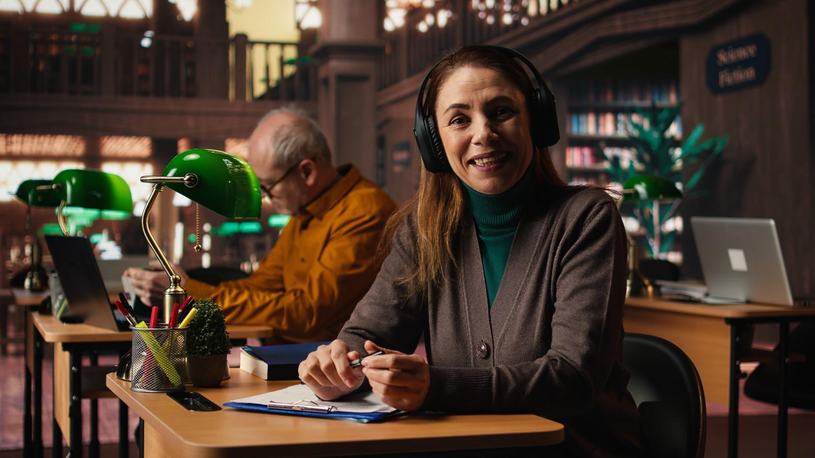 Professional studying at a library desk with headphones
